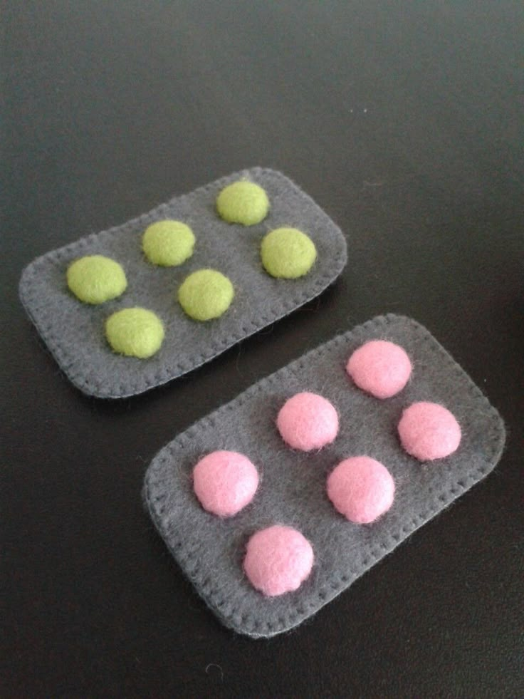 two felt coasters with pink and green balls on them next to a cup of coffee