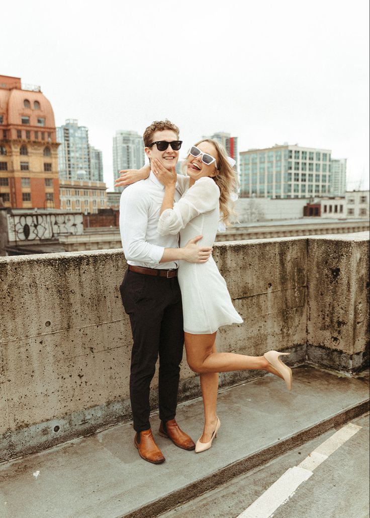 a man and woman standing on top of a roof with their arms around each other