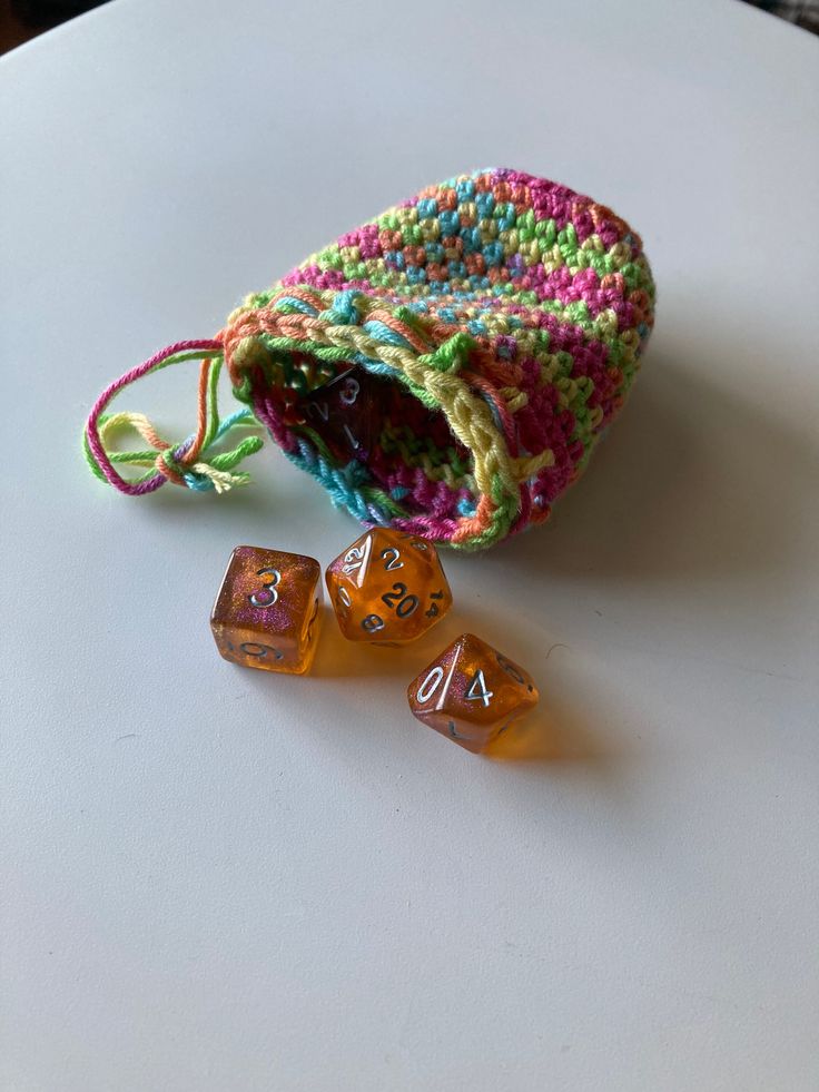 two dice bags sitting on top of a table next to some orange and green dice holders