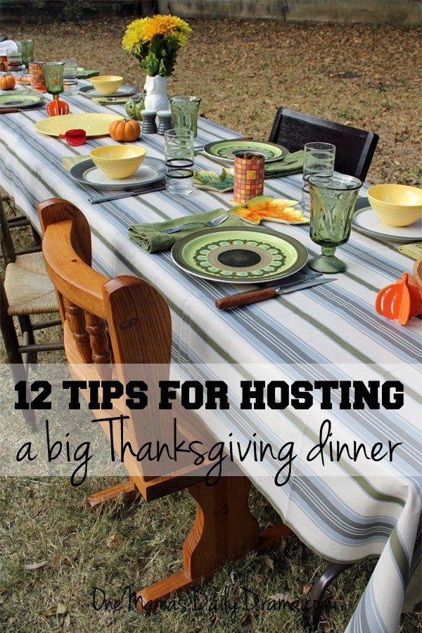 a long table set for thanksgiving dinner with plates and glasses on it in the grass