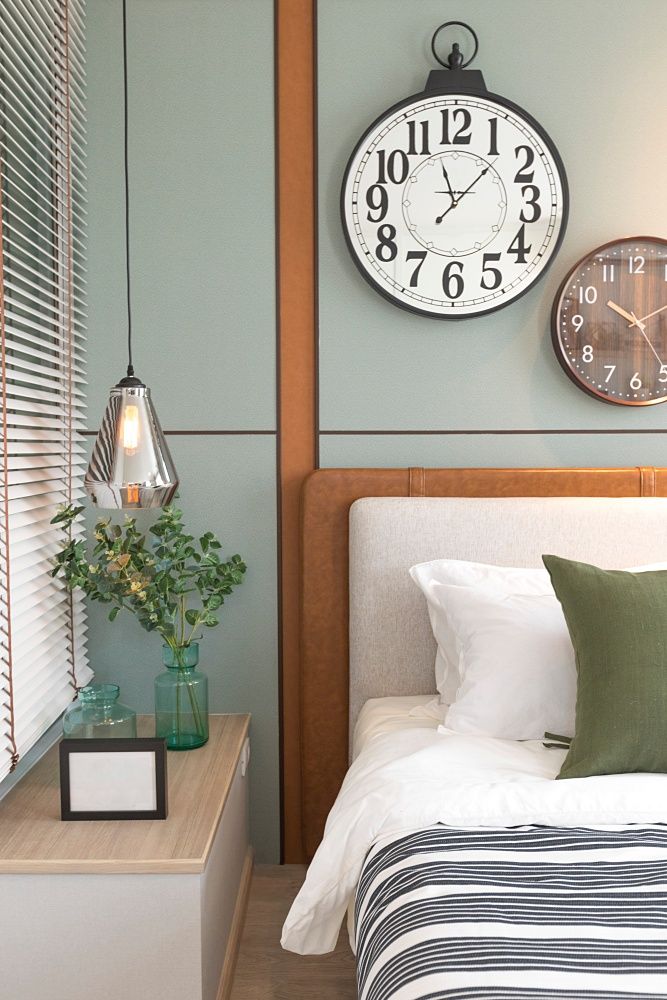 a bedroom with a bed and two clocks on the wall above it's headboard