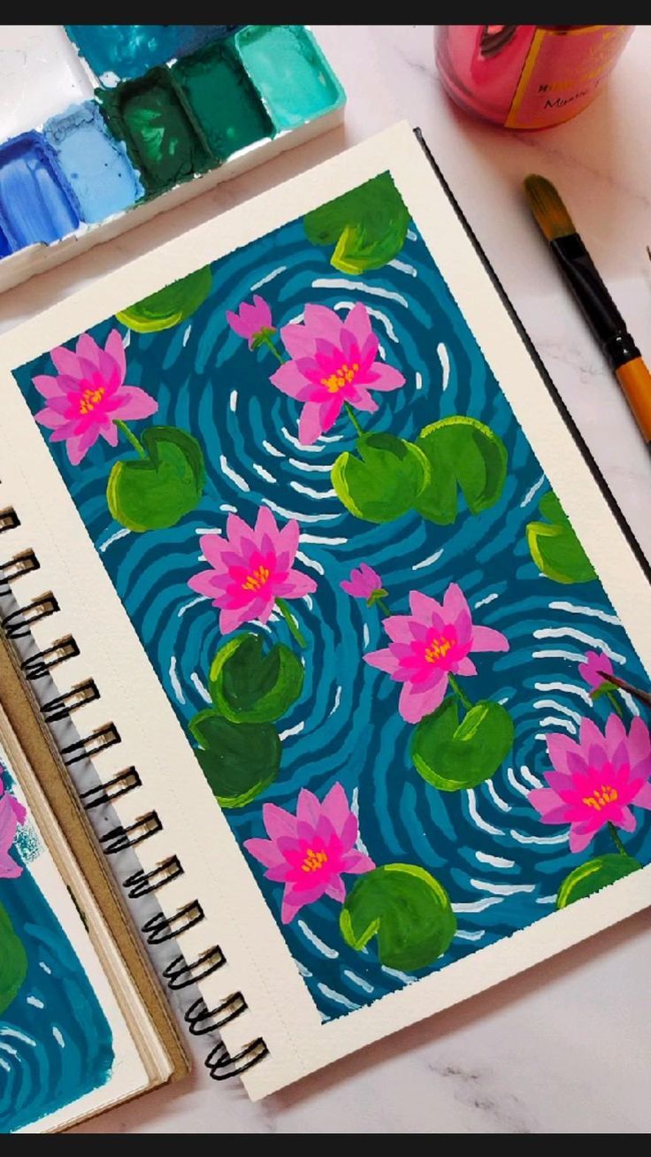 two notebooks with water lilies on them next to paintbrushes and markers