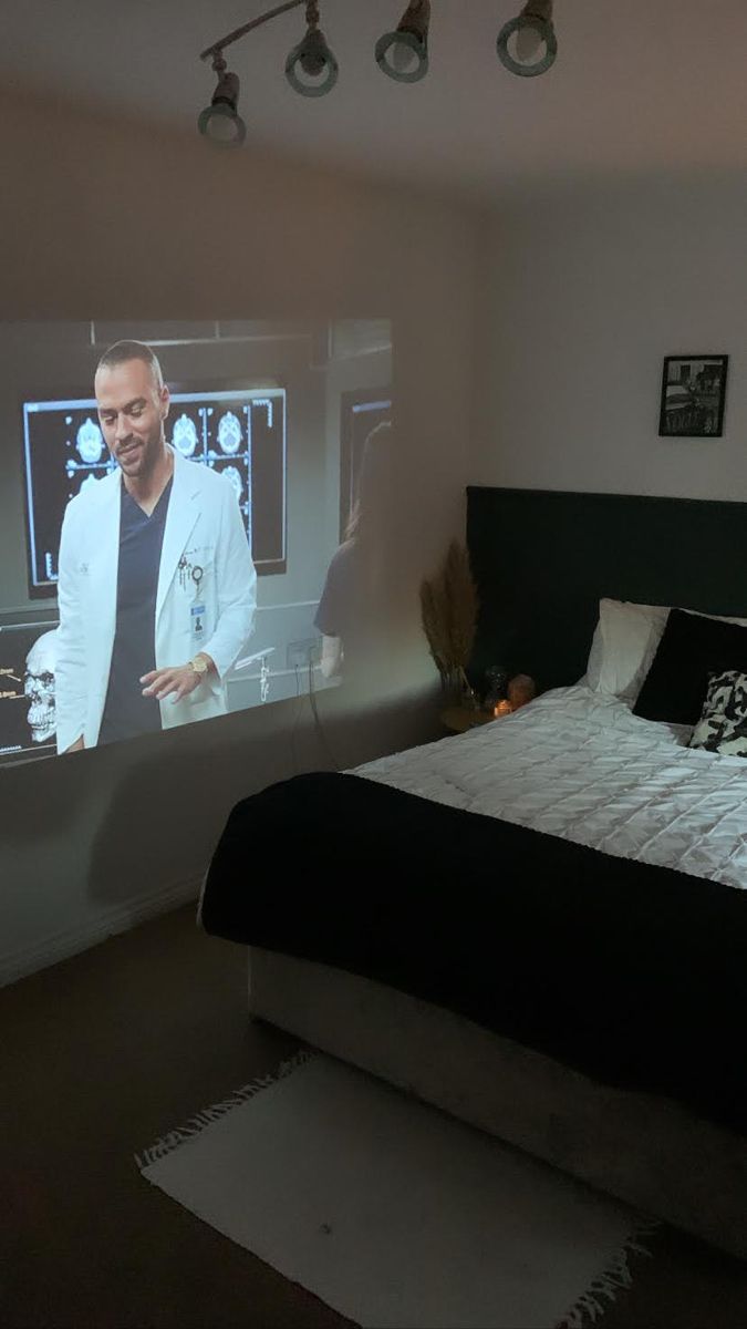 a bed in a room with a large screen on the wall