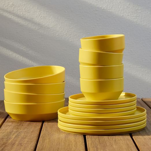 a stack of yellow plates sitting on top of a wooden table