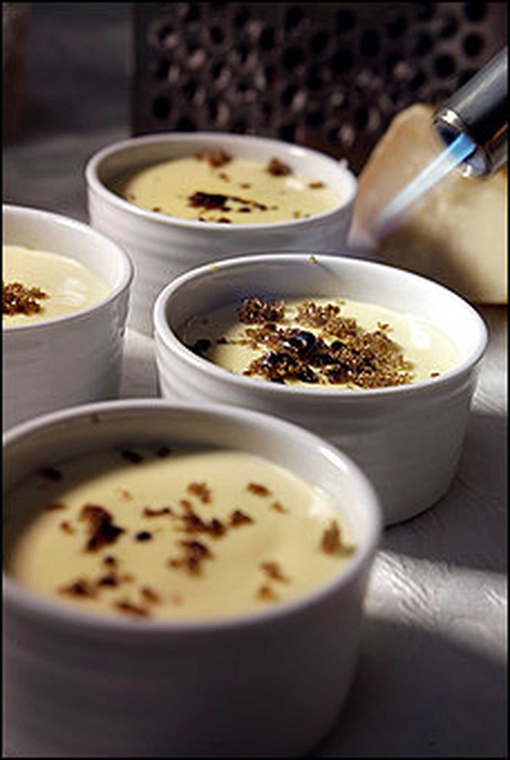 four white bowls filled with soup on top of a table