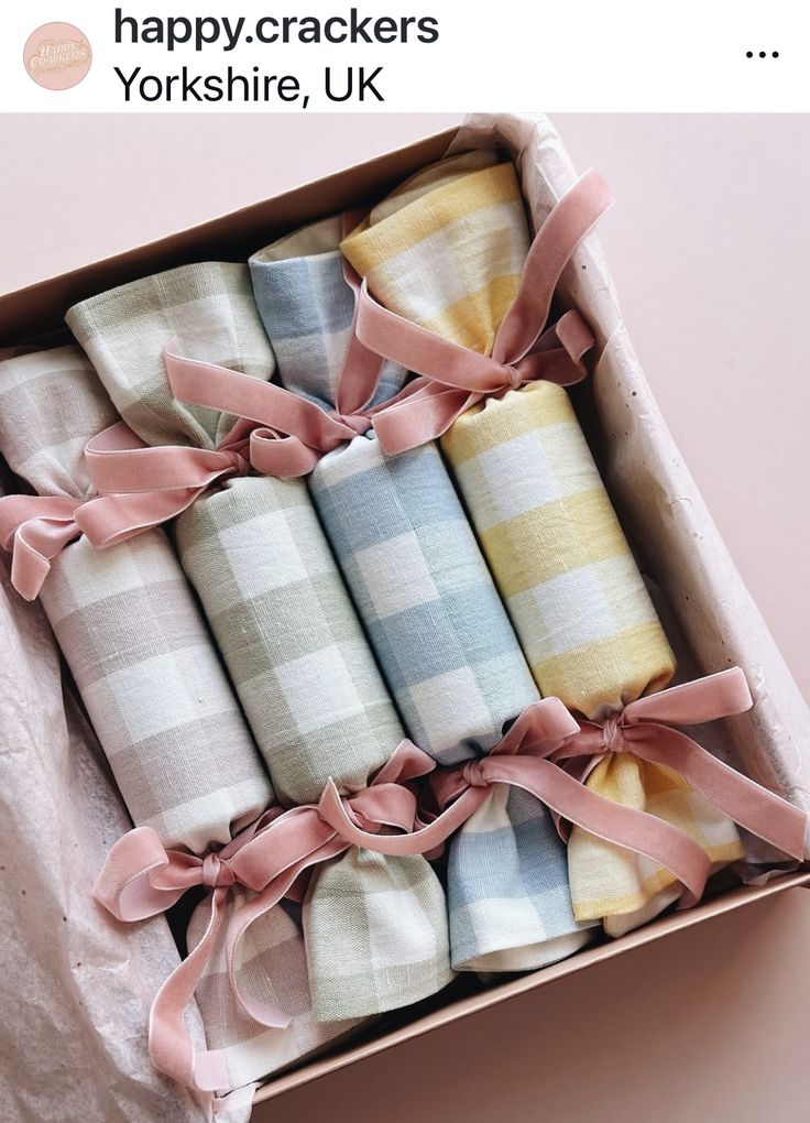 a box filled with baby blankets on top of a pink table cloth covered in ribbon