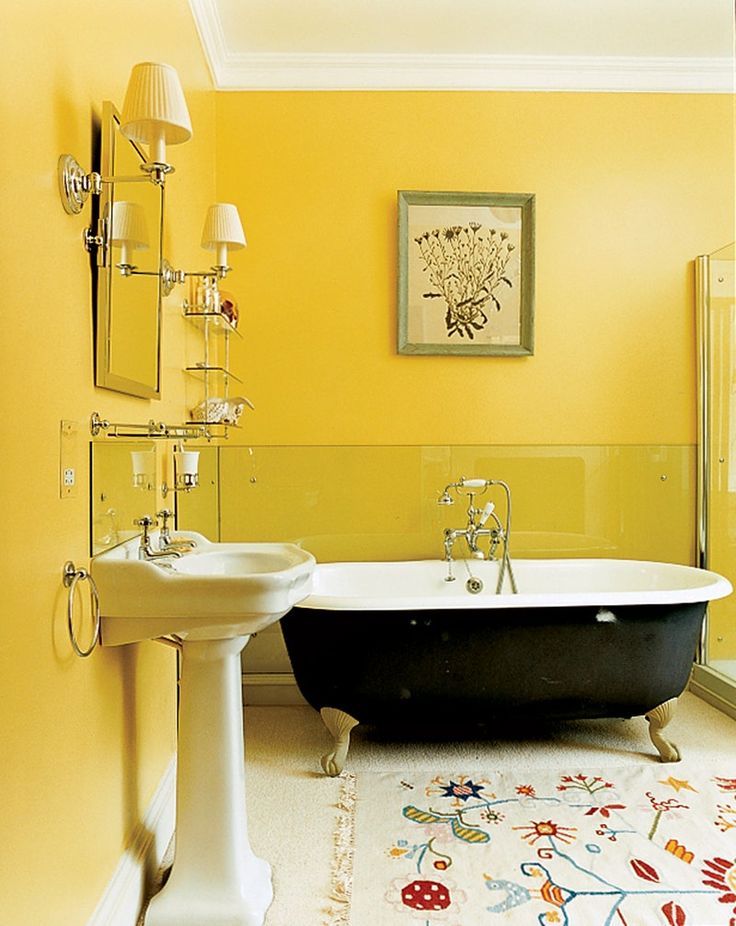 a bath tub sitting next to a white sink in a bathroom under a painting on the wall