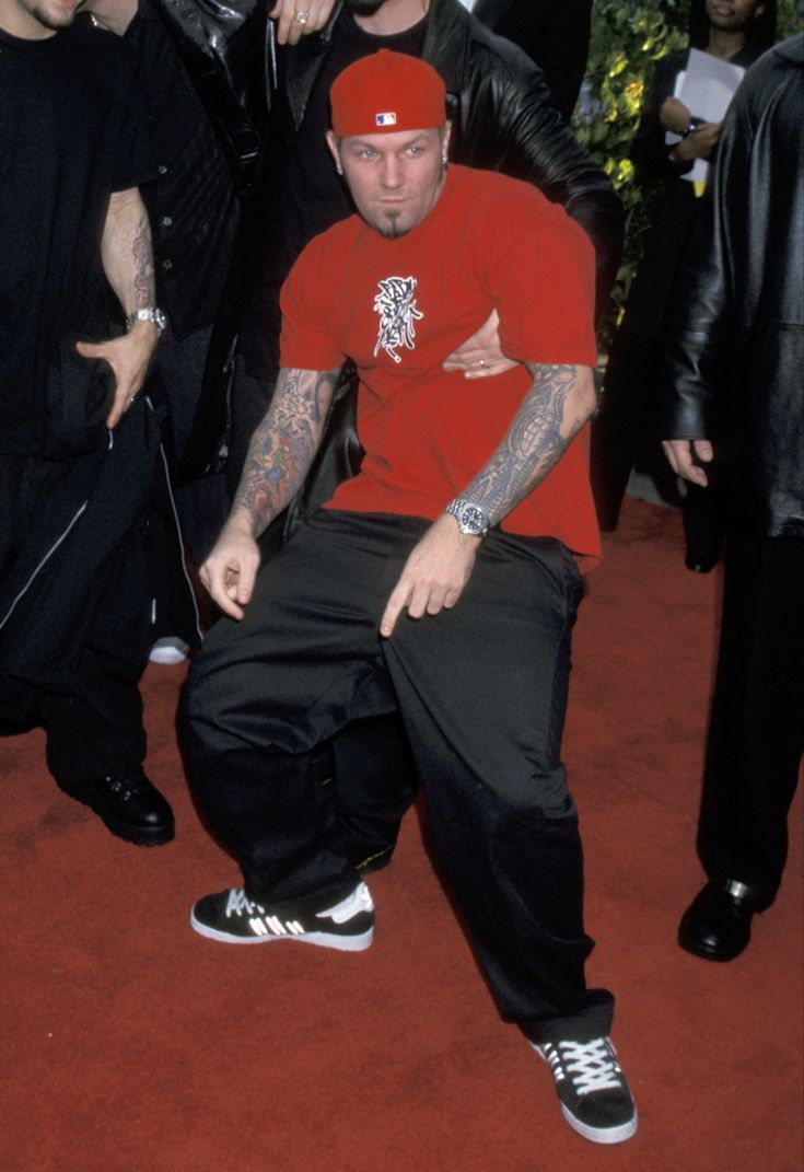 a group of men standing next to each other in front of a person wearing a red shirt