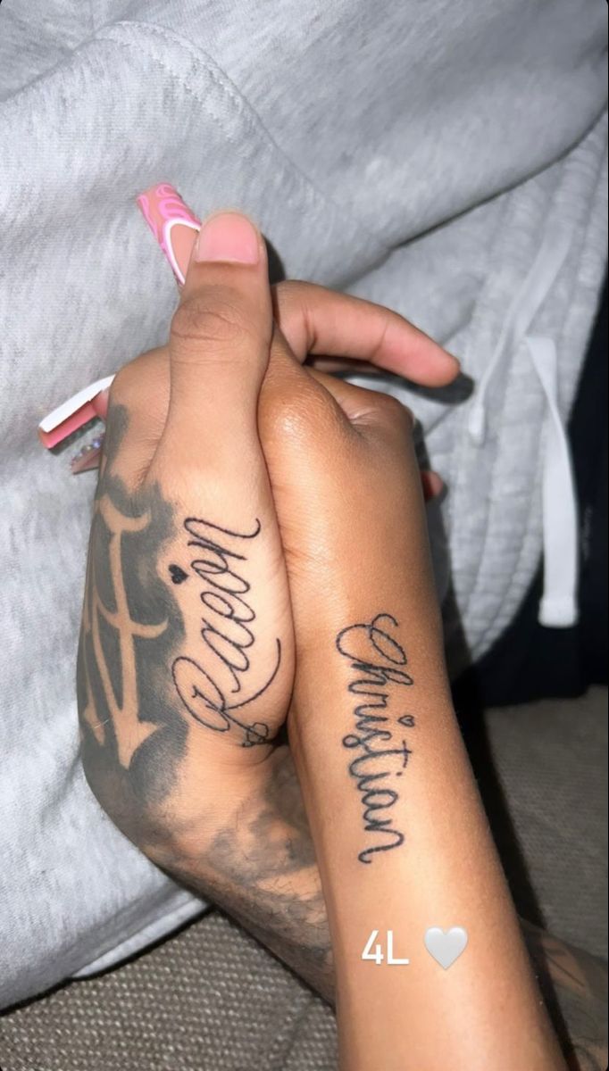 two people holding hands with tattoos on their arms and the other hand has writing on it