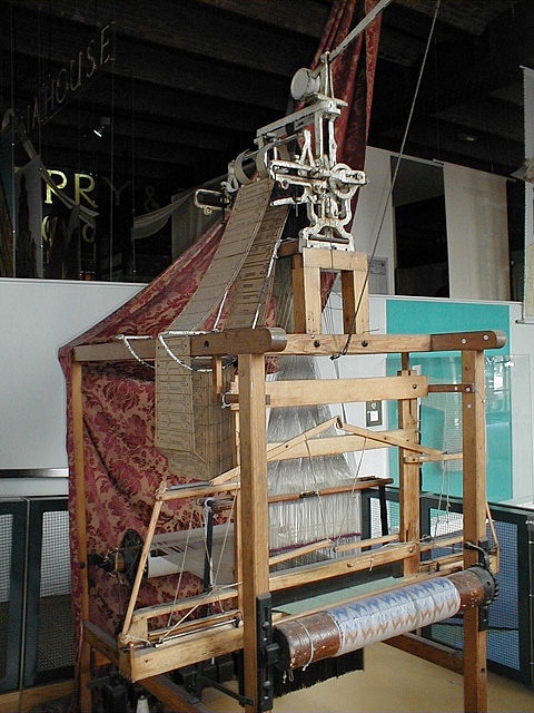 an old weaving machine is sitting in the middle of a room with other items on it