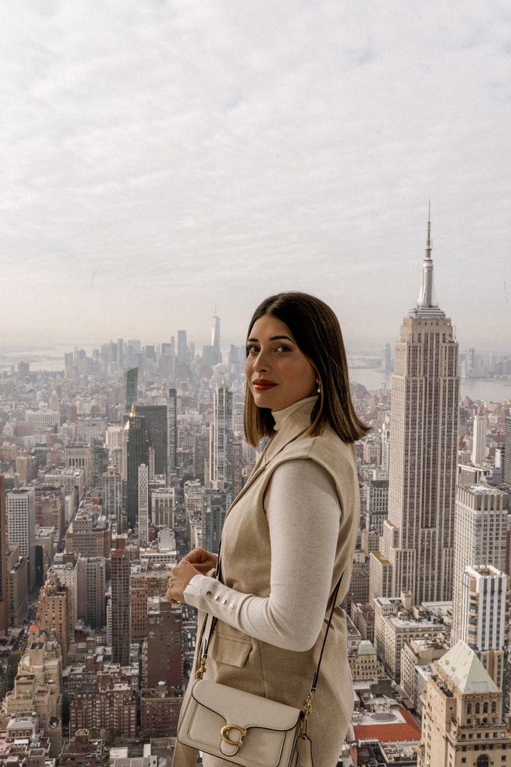 a woman standing on top of a tall building looking at the cityscape behind her