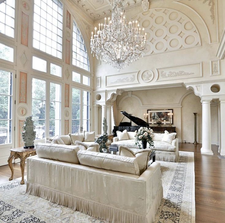 a living room filled with lots of furniture and a chandelier hanging from the ceiling