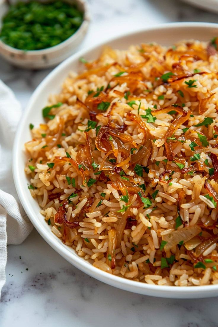 a white bowl filled with rice covered in sauce and garnished with green onions