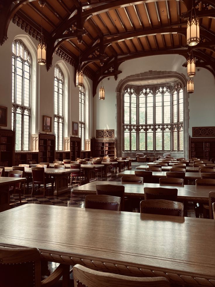 a large room with tables and chairs in it's center, surrounded by tall windows