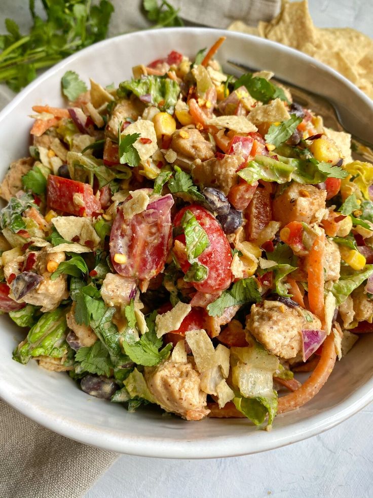 a white bowl filled with salad and tortilla chips on top of a table