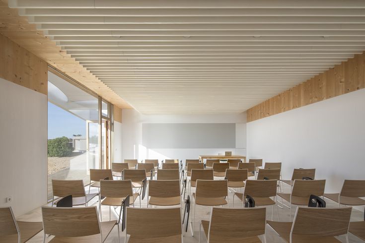 an empty classroom with wooden chairs and white walls