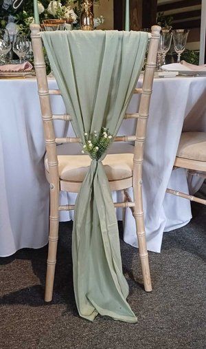 a chair with a green sash on top of it next to a white table cloth