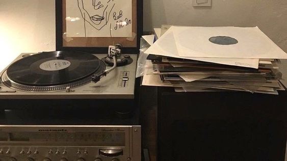 a record player sitting on top of a table next to a pile of papers and records