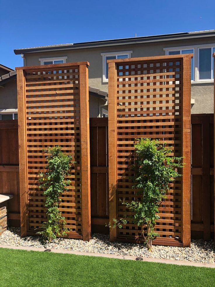 a wooden fence in front of a house with plants growing on the top and bottom