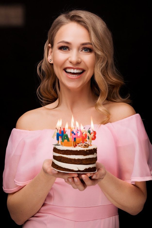 a woman holding a birthday cake with lit candles