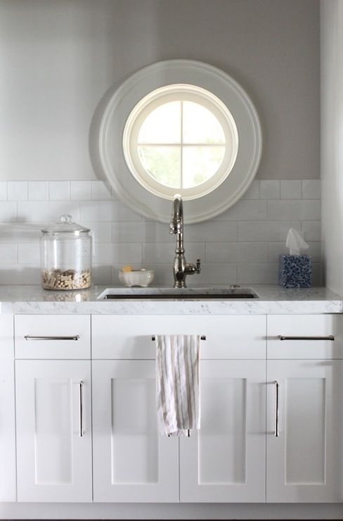 a kitchen with white cabinets and a round window