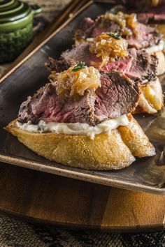 a roast beef sandwich is on a wooden platter