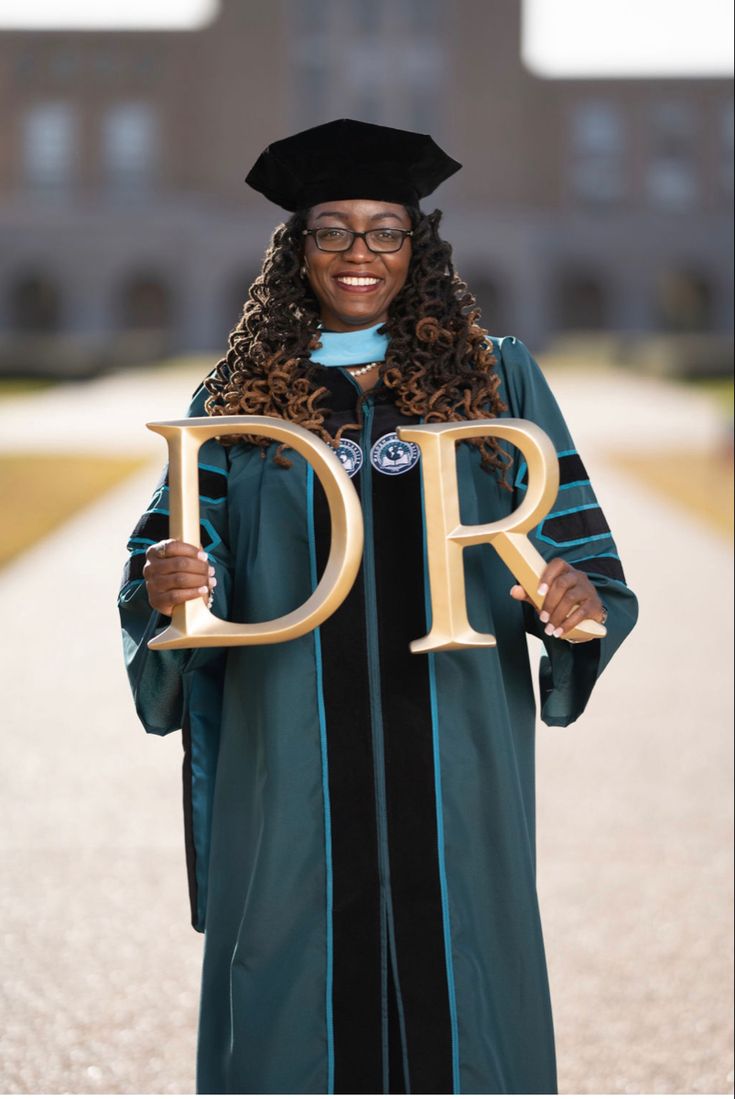 a woman in graduation gown holding the letter dr