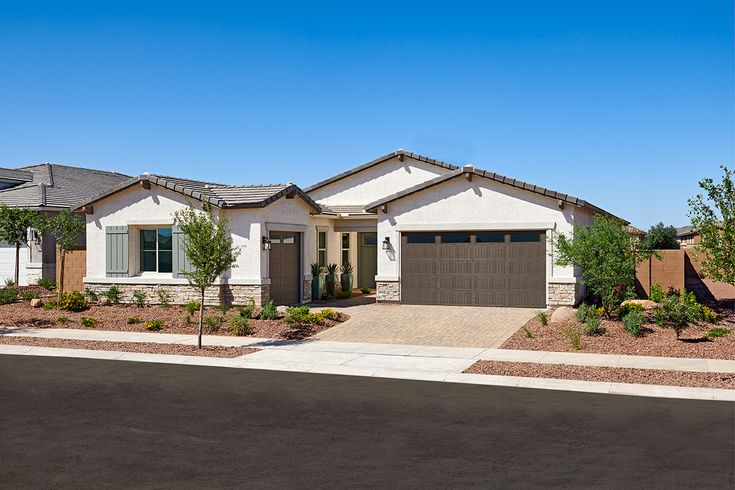 a house with two garages in front of it and landscaping around the driveway area