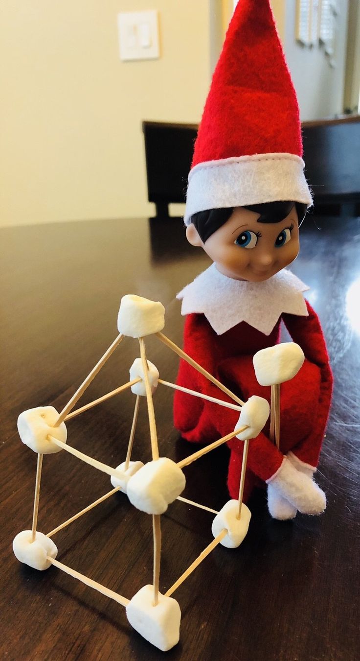 an elf is sitting next to a ferris wheel on the table with marshmallows