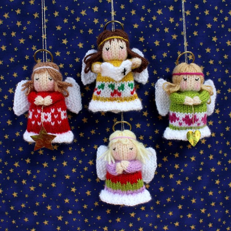 christmas ornaments with angels hanging from them on a blue cloth covered tablecloth and gold stars