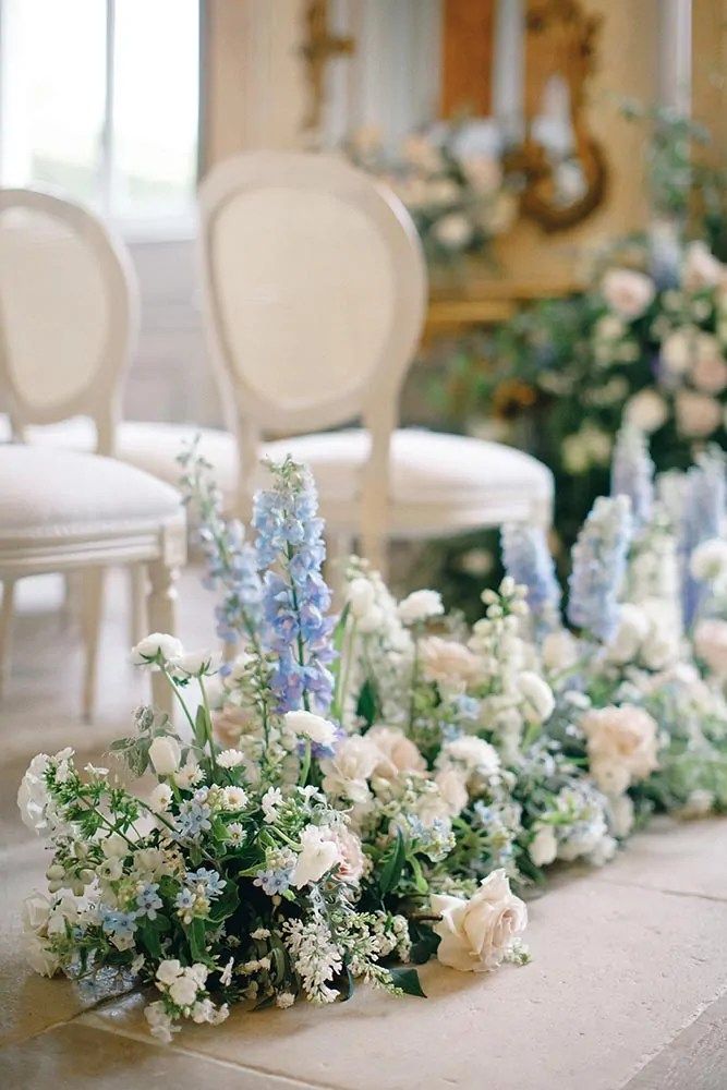 the chairs are lined up with flowers and greenery