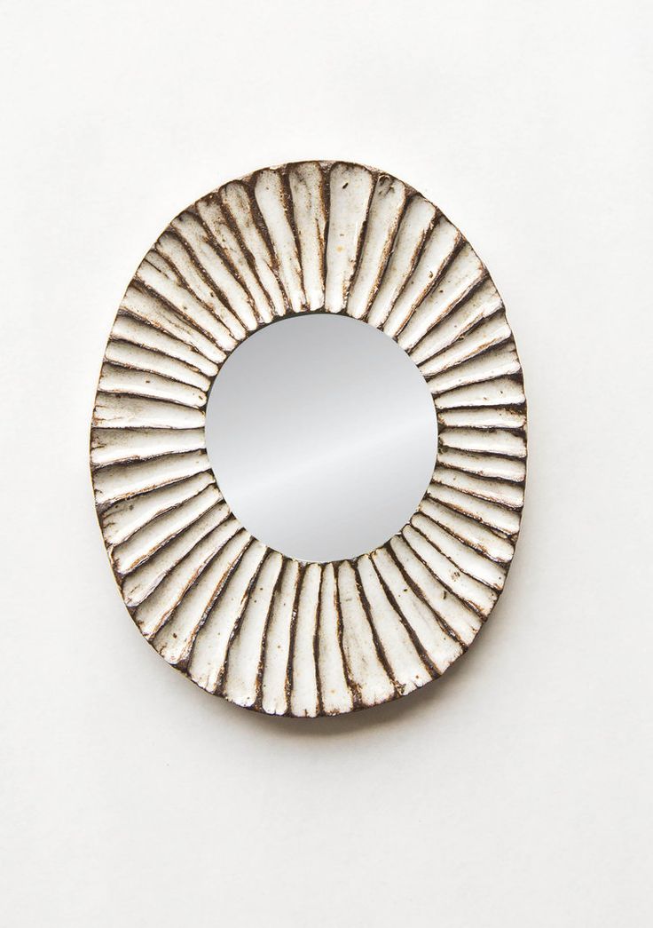 a round mirror sitting on top of a white wall