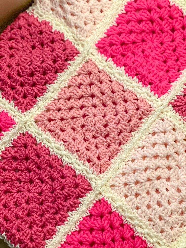 a pink and white crocheted blanket sitting on top of a table