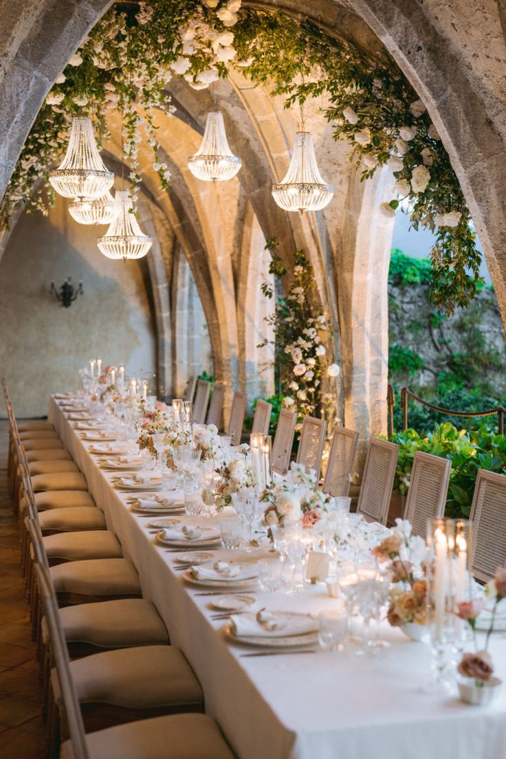 a long table is set with white linens and flowers