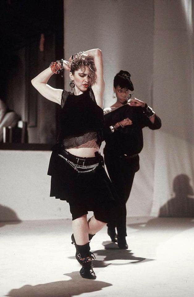 two people are dancing on the runway in black outfits and hats with chains around their necks