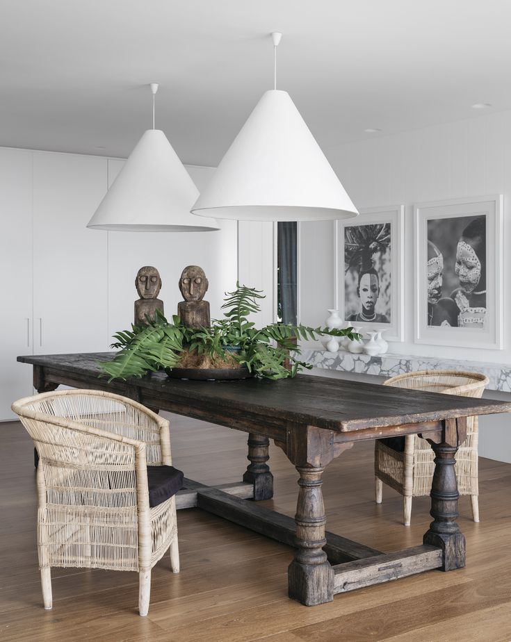 a dining room table with chairs and pictures on the wall in the backround