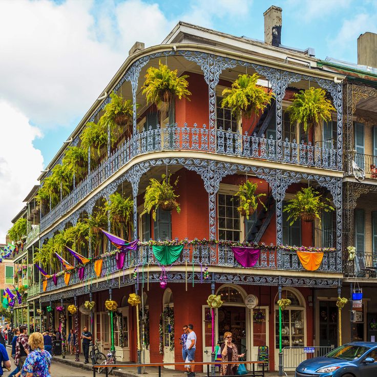 people walking on the sidewalk in front of an old building with colorful balconies