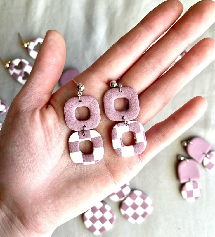 a hand holding some pink and white earrings