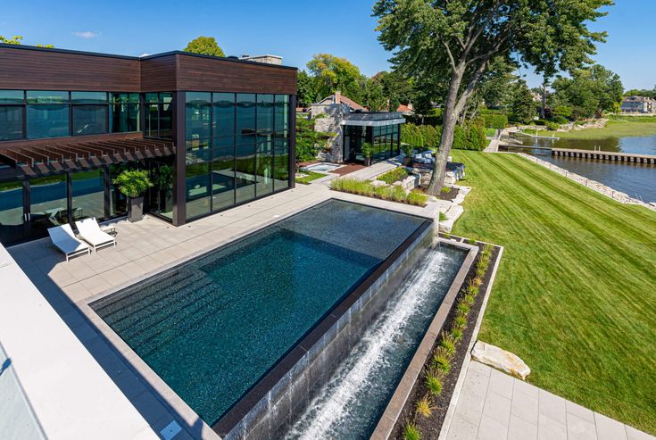 an aerial view of a house with a pool in the foreground and a lake behind it