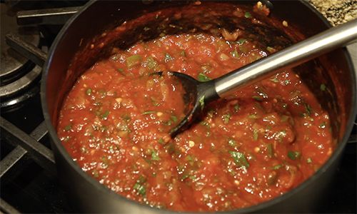 a pot filled with red sauce sitting on top of a stove