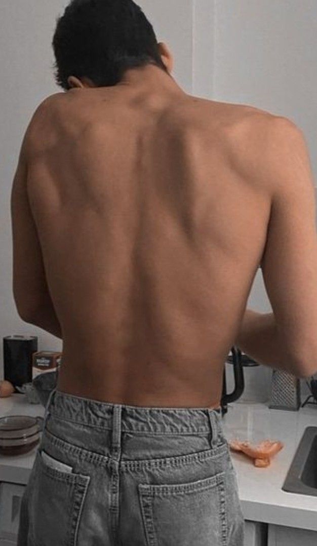 a man standing in front of a kitchen sink with his back turned to the camera