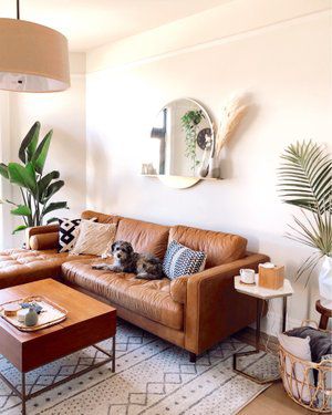 a living room with a brown leather couch and coffee table in front of a mirror