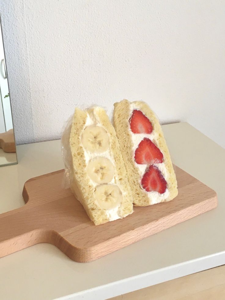 two slices of banana and strawberry sandwich sitting on a cutting board next to a mirror