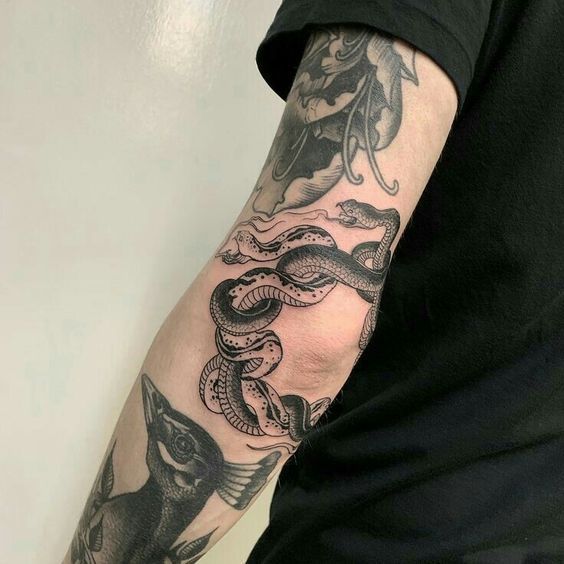 a man's arm with tattoos on it and a snake wrapped around the arm