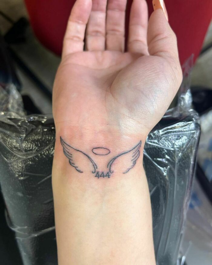 a woman's hand with a small tattoo on the wrist and an angel wing