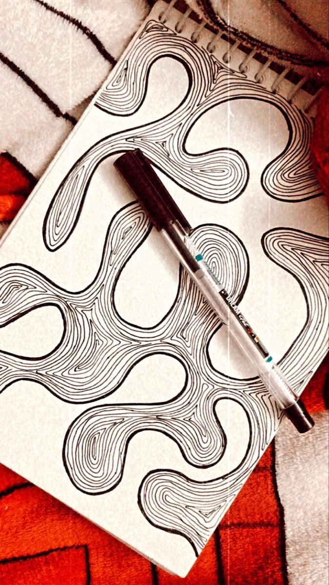 a pen sitting on top of a notebook next to an orange and white cover with swirls