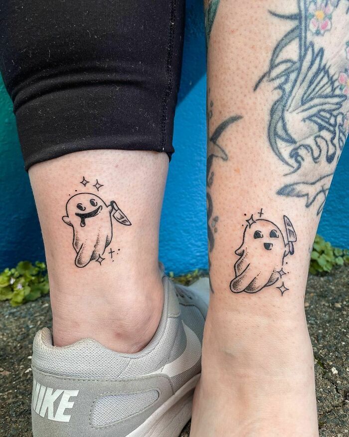 two people with matching tattoos on their legs, one has a dog and the other has a cat