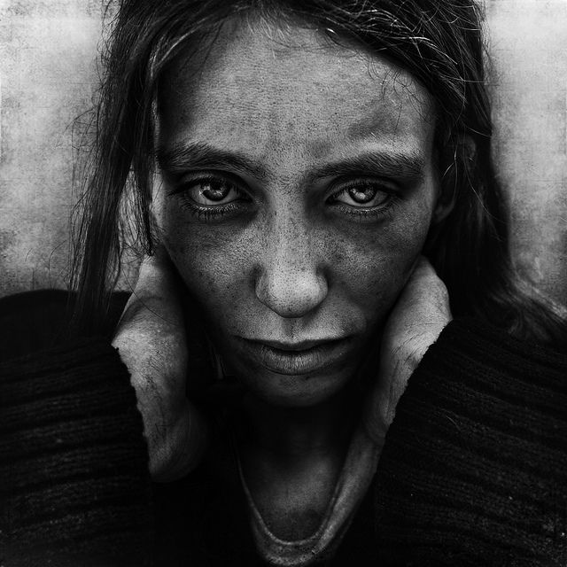 a black and white photo of a woman's face with her hands on her ears