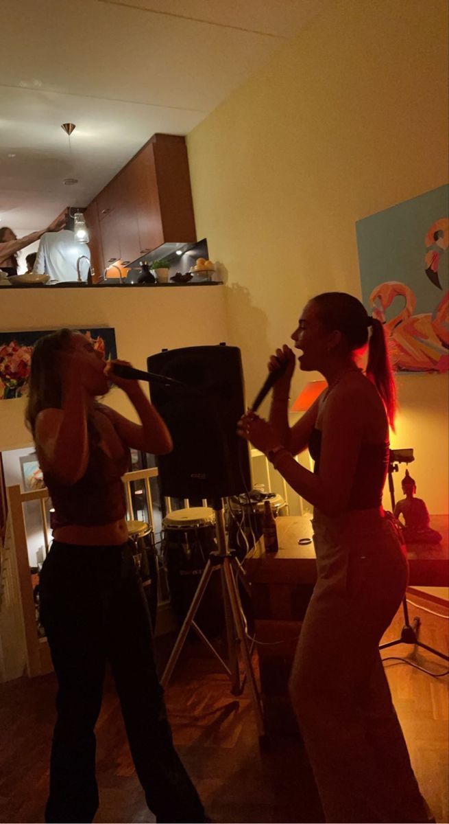 two women are singing into microphones in a living room