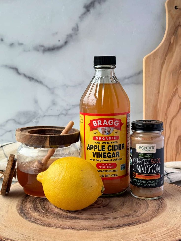 ingredients for apple cider vinegar sitting on top of a wooden table next to a cutting board